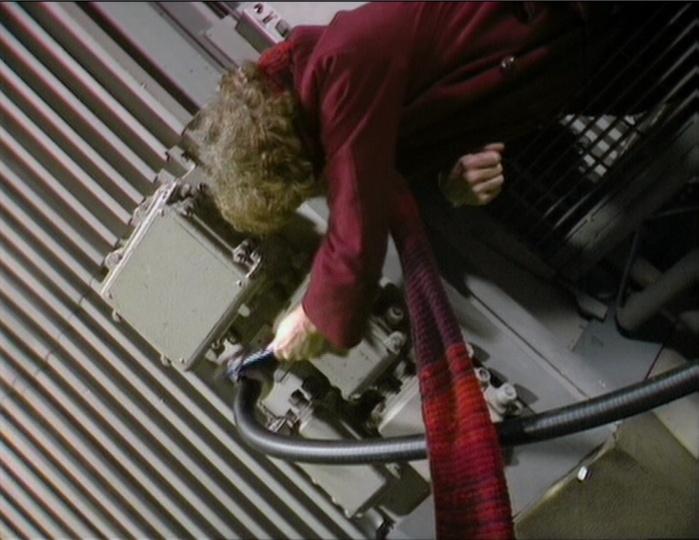 The Doctor unhooks the transmission cable from atop a high gantry